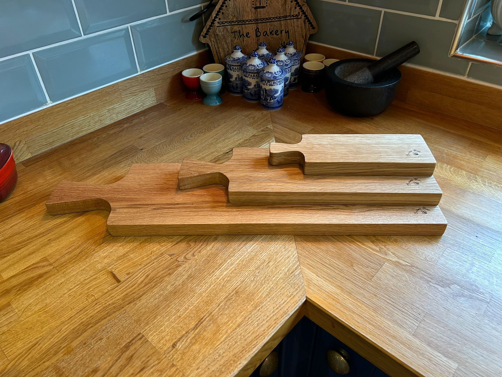 A picture of three solid oak serving platters, one on top of the other, on a kitchen worktop