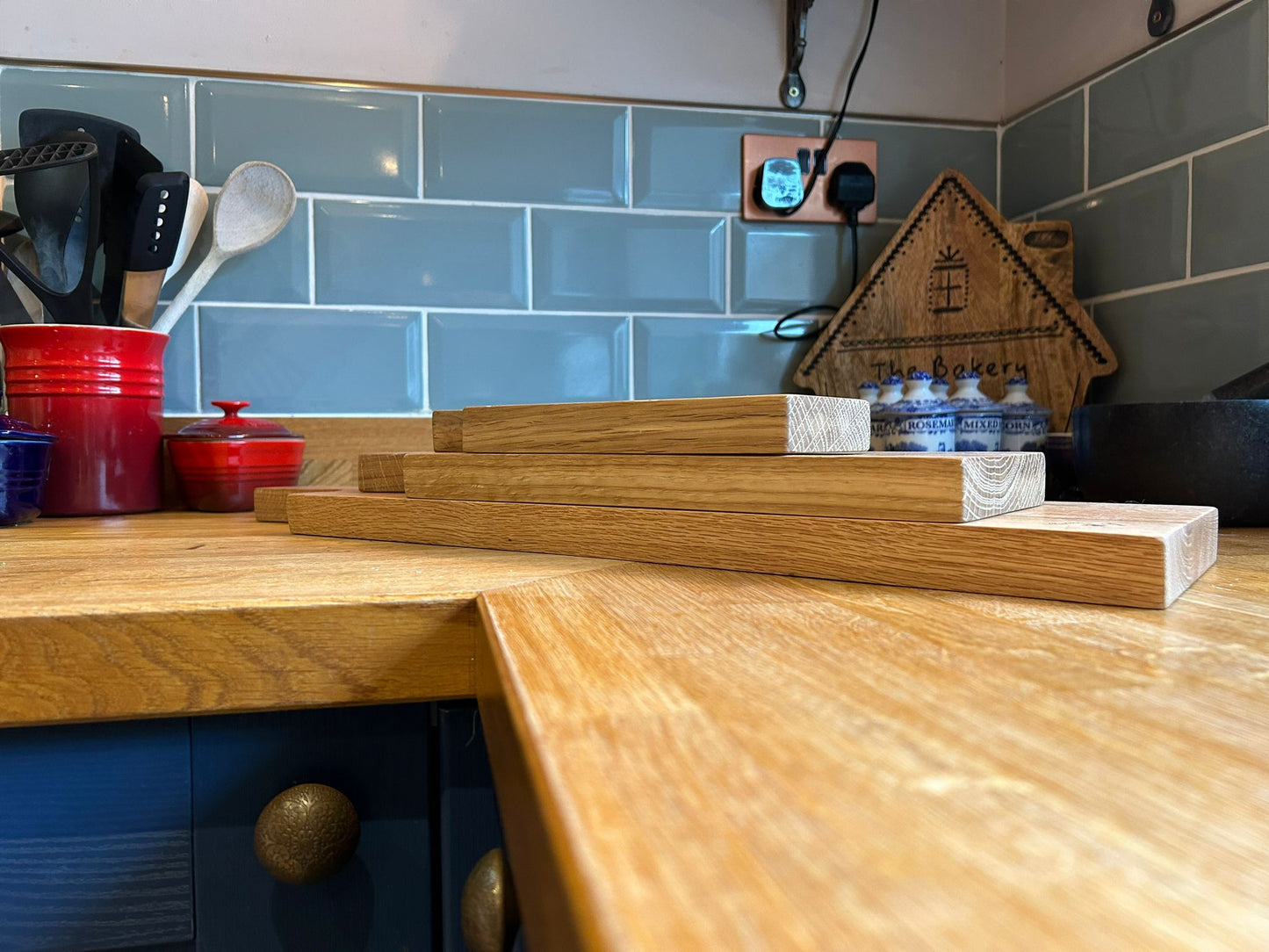 A picture of three solid oak serving platters, one on top of the other, on a kitchen worktop